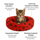 Kitten sitting in a red zigly plush velvet pet bed with black paw and leaf patterns, calming doughnut shape