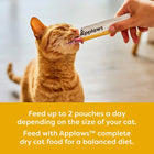 Zigly ginger cat licking Applaws puree treat from tube, indoor feeding, cat snack