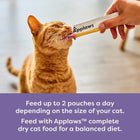 Orange cat licking Applaws cat food treat stick, zigly, indoors with feeding instructions.