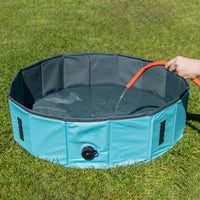Zigly portable blue pet water pool being filled with hose on green grass outdoors