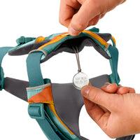 Close-up of teal and orange dog harness with hands attaching Ruffwear dog ID tag, zigly