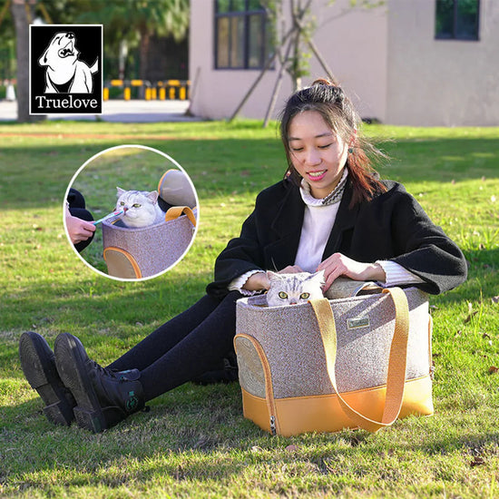 Woman sitting on grass petting a cat in a textured pet carrier bag with beige straps, branded Truelove, zigly