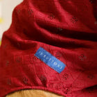 Zigly red patterned pet clothing with blue 15 BUTTONS label, close-up fabric texture