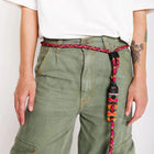 Person wearing green pants and white shirt with a pink and orange woven rope belt featuring a zigly clasp