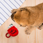 Zigly pug dog lying on wooden floor next to red plush toy mug labeled Santa's Favorite