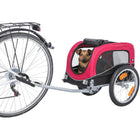 Dog riding in a red pet bike trailer attached to a bicycle, zigly safe pet transport
